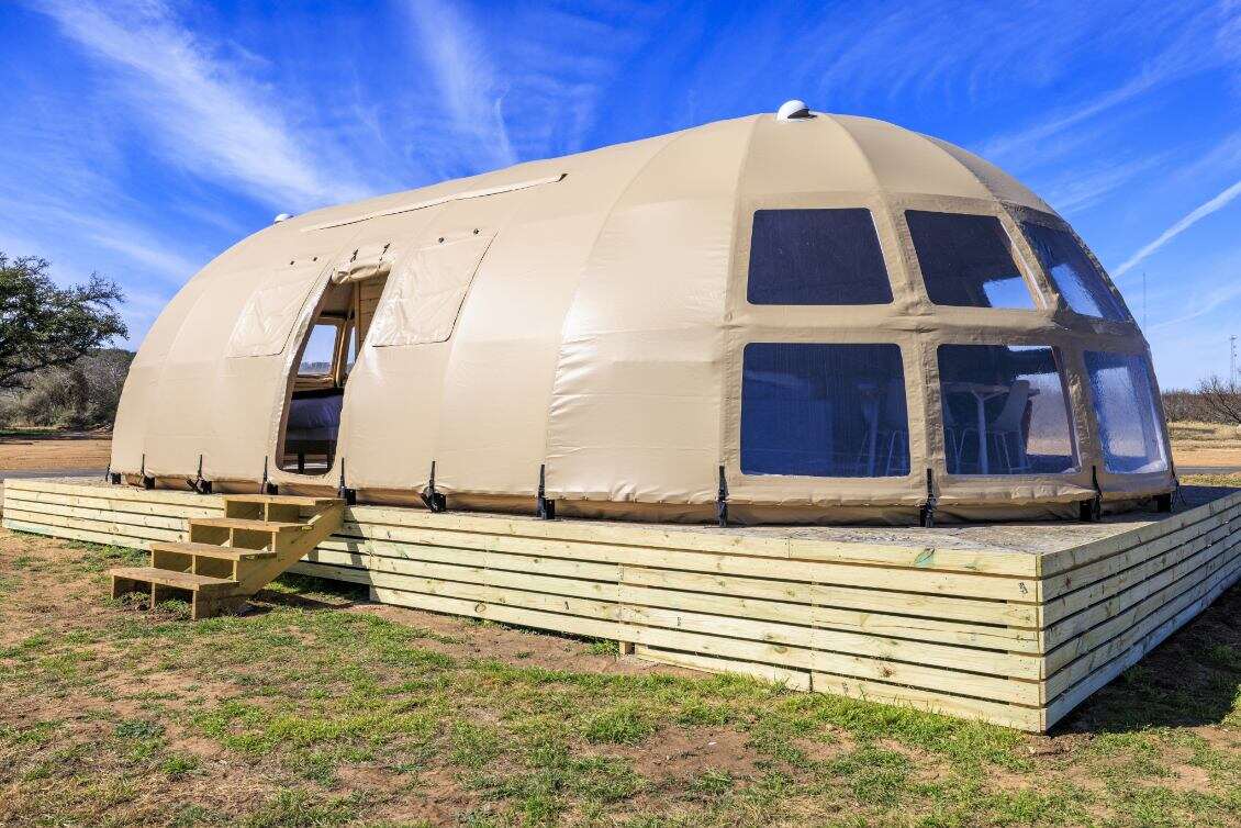 Alt text: &quot;Spacious geodesic dome with porthole windows on a wooden platform, ideal for glamping or a luxury Airbnb experience. This large dome tent offers a stylish and sustainable living solution, perfect for a backyard dome or geodesic home setup.&quot;
