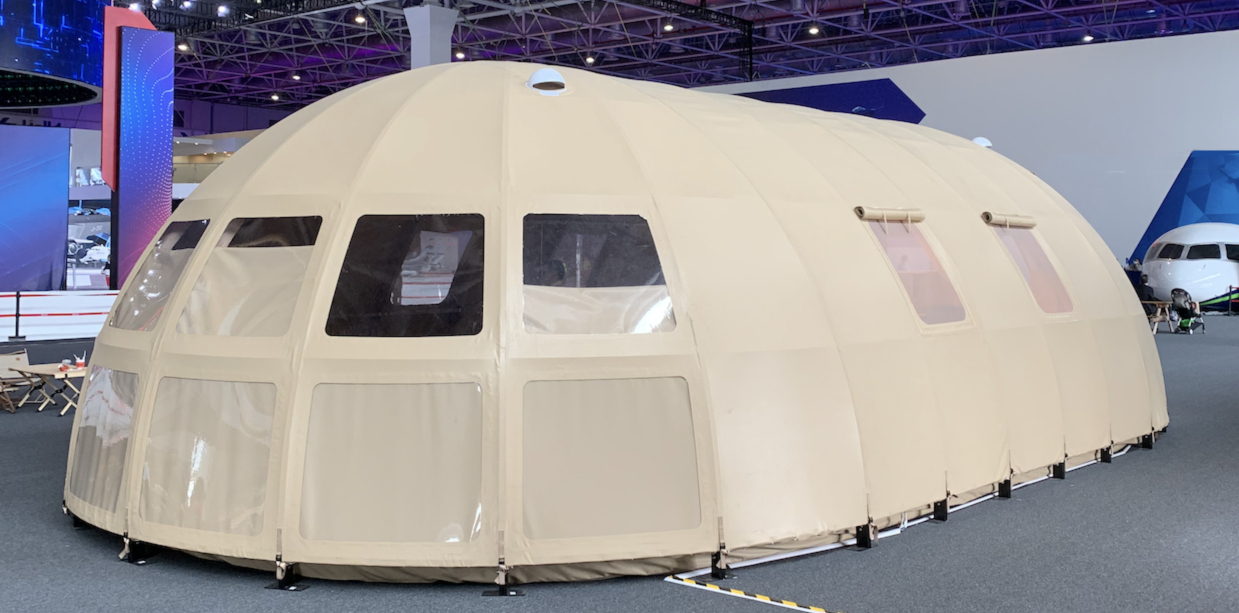 Alt text: &quot;Large beige geodesic dome tent with porthole windows, showcased indoors. Ideal for glamping, sustainable living, or as a luxury Airbnb option. High-quality and stylish design for diverse needs.&quot;